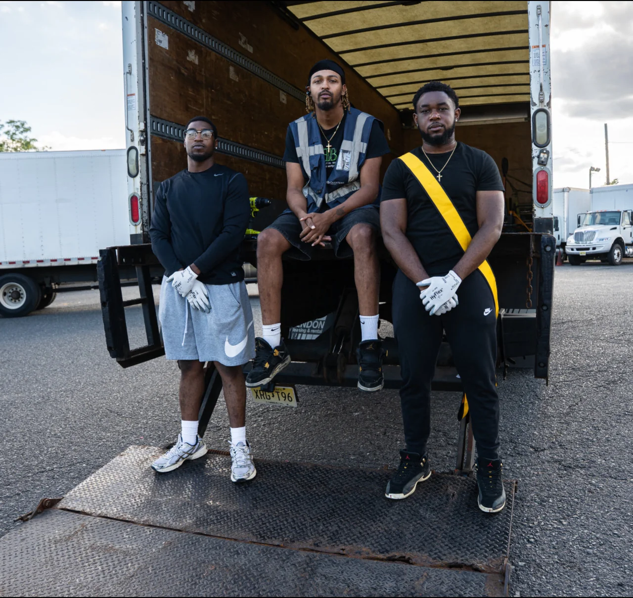 Haul Yeah Moving three-man crew posed on the liftgate of a 26-ft moving truck, with the middle crew member in a safety vest